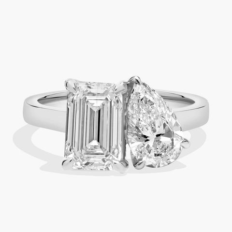14K white gold ring featuring emerald-cut and pear-shaped diamonds side-by-side in a modern prong setting.